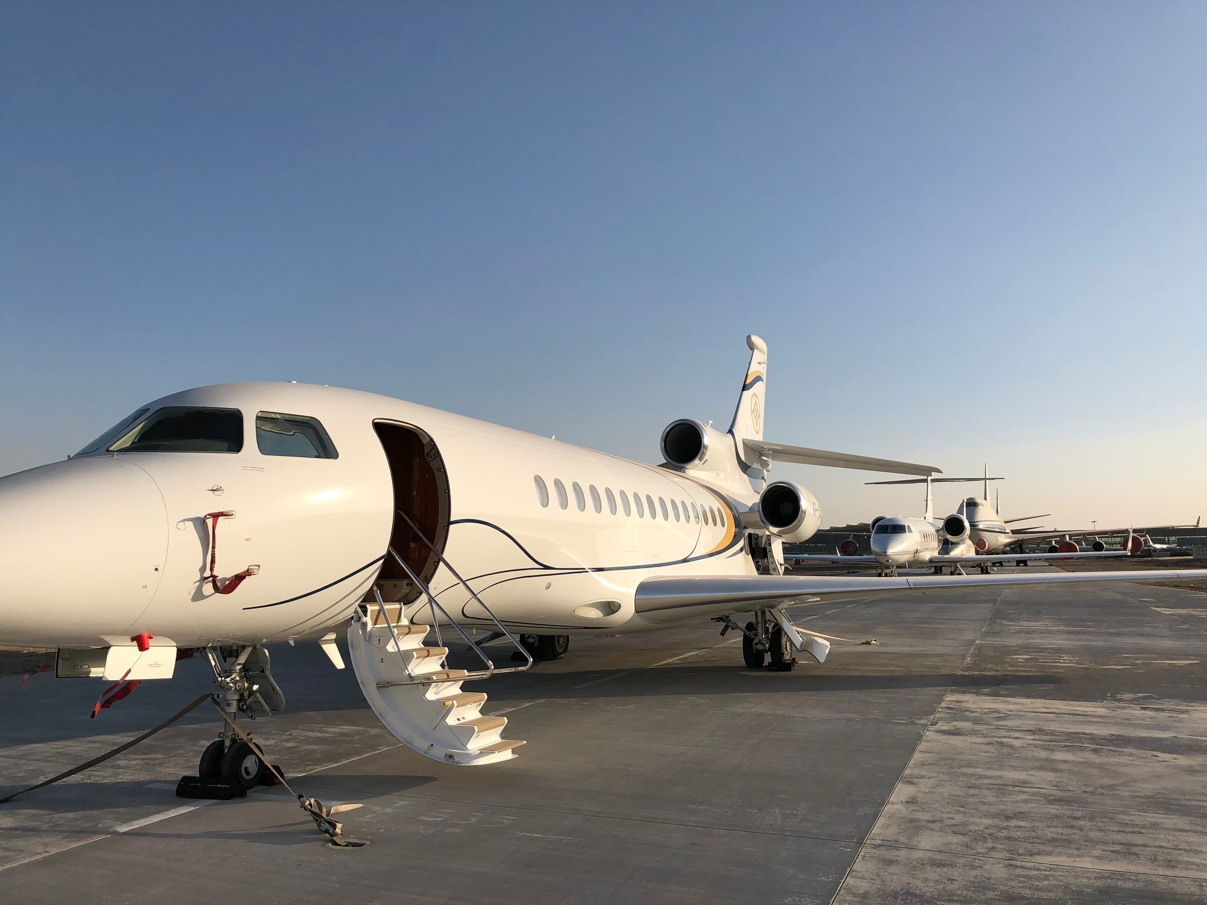 Row of Falcon business jets on the apron at sunset